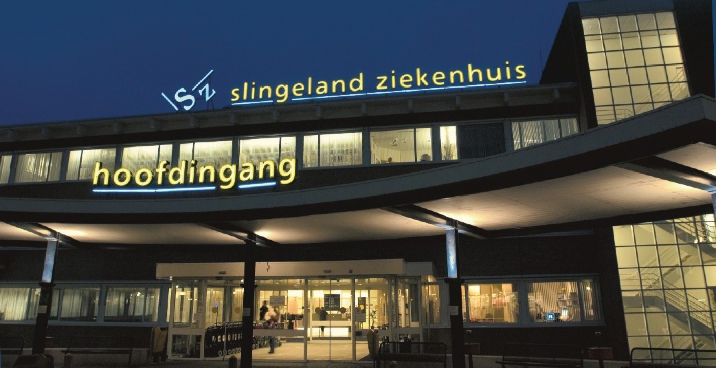 De hoofdingang gefotografeerd in de avond. 