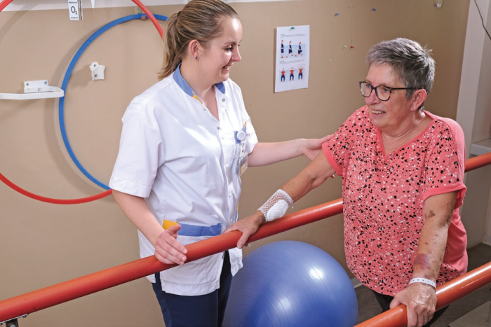 Fysiotherapeut Cynthia Evers geeft patiënt Ine van Bommel instructie op de brug.