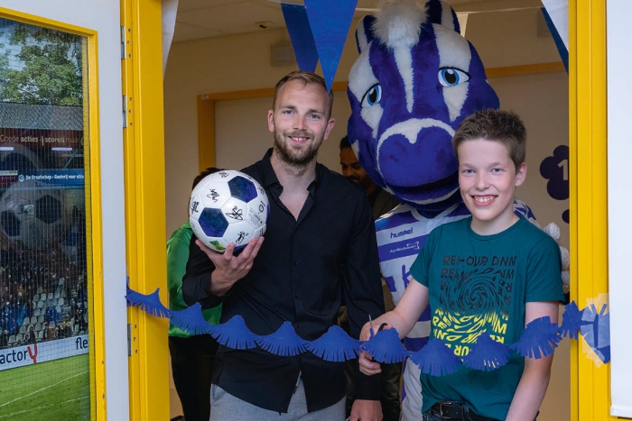 Patiënt Lars en De Graafschap-keeper Hidde Jurjus openen de Graafschapkamer op de Kinderafdeling met mascotte Guus.