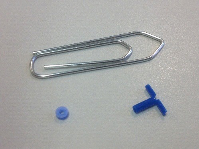 De afmeting van twee trommelvliesbuisjes ten opzichte van een paperclip die 4  tot 10 keer groter is.