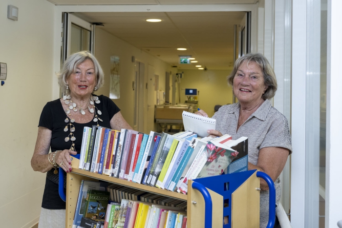 Vrijwilligers Anneke Bastiaanse (links) en Lidwine van Iersel gaan rond met de boekenkar.