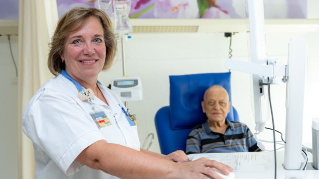 Angela Jansen aan het werk op de computer bij een patiënt op de dagbehandeling Oncologie. Foto: Toon Hendriks