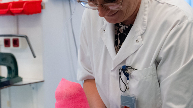 Gipsverbandmeester Eva Schabbink brengt roze gips aan op een voet.