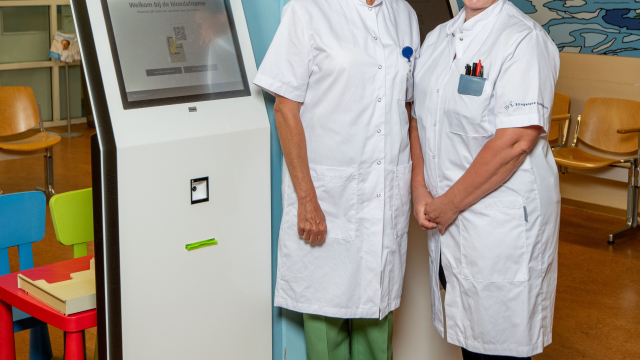 Mirjam Schepers en Petra Kunkels bij een aanmeldzuil voor bloedafname.