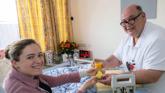Medewerker gastenservice René overhandigt een smakelijk en gezond tussendoortje aan patiënte Femke .