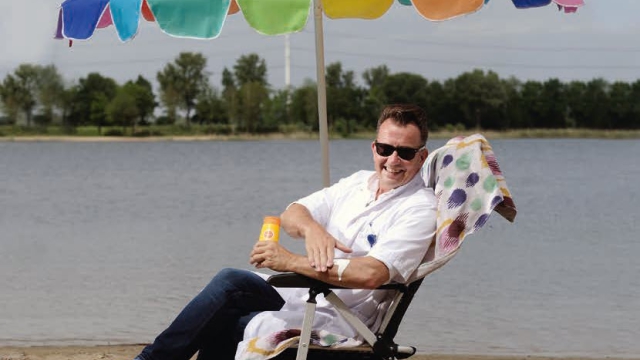 Dermatolog Rob Veenhuis aan de recreatieplas Stroombroek met parasol en zonnebrand.